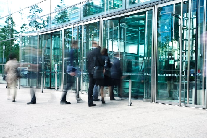 A group of business people walking into an office building.