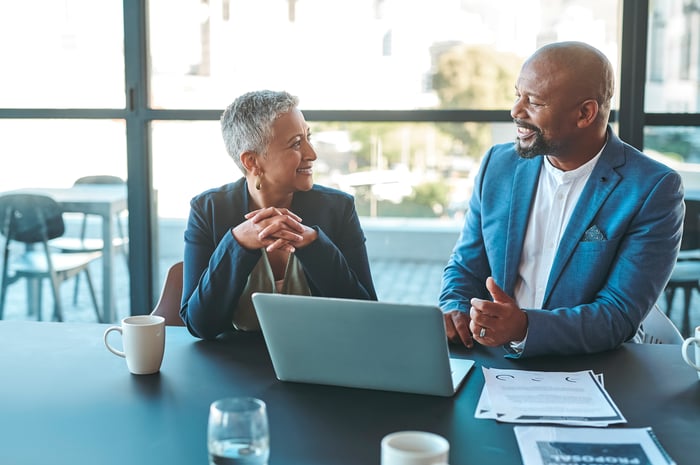 Two people discussing financial planning in front of an open laptop.