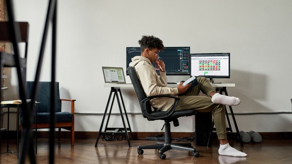 A young man looking at a book with a chart in the background.