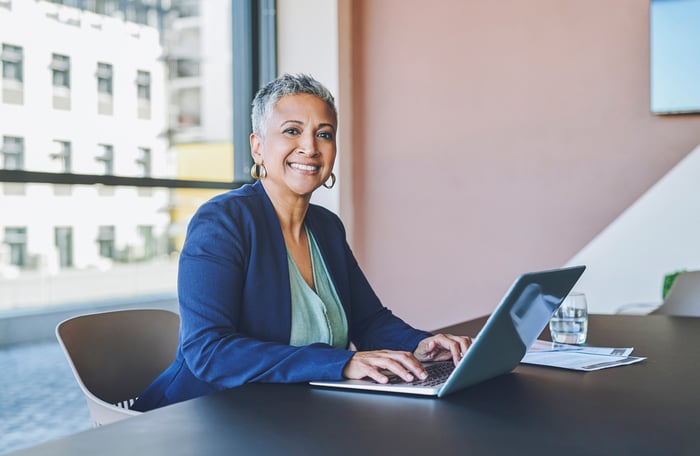 A smiling person at a laptop.