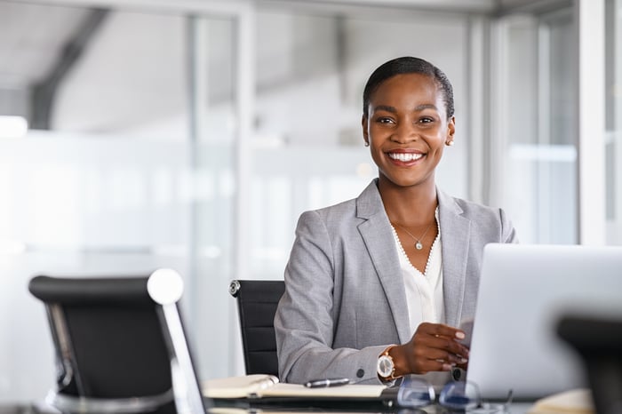 A smiling person at a desk.
