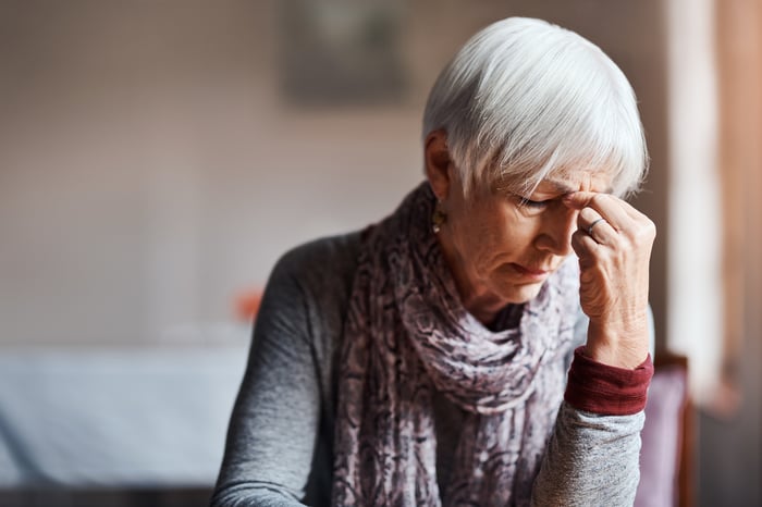 A person with closed eyes pinching the top of their nose.