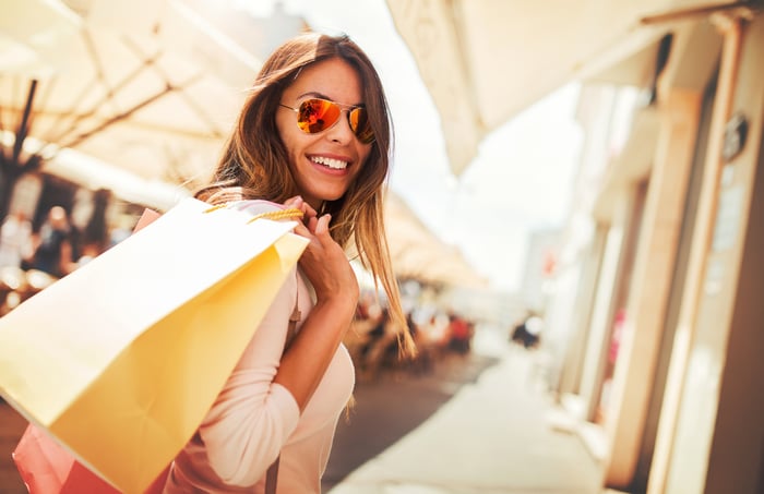 A smiling person shops at an outdoor mall.