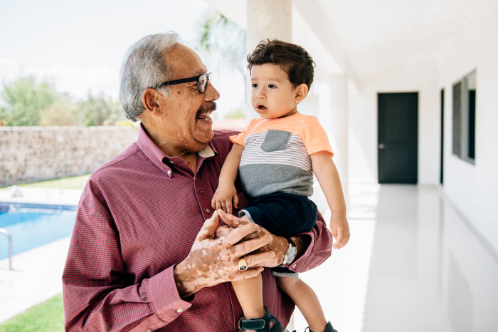 A person smiling and holding a child.