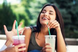 Young woman laughing and drinking soda