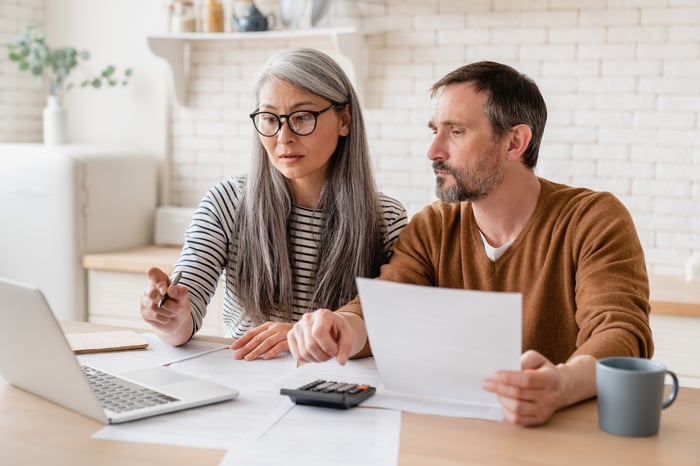 Two people looking at laptops and paperwork.