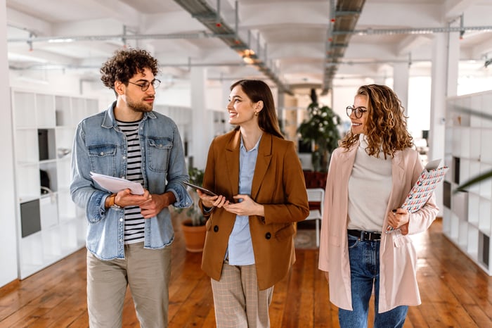 Three Gen Z workers walking in an office. 