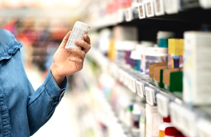 A hand holding a bottle of vitamins or medicine.