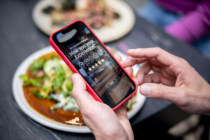 A person rating their experience at a restaurant using an app on a cell phone.