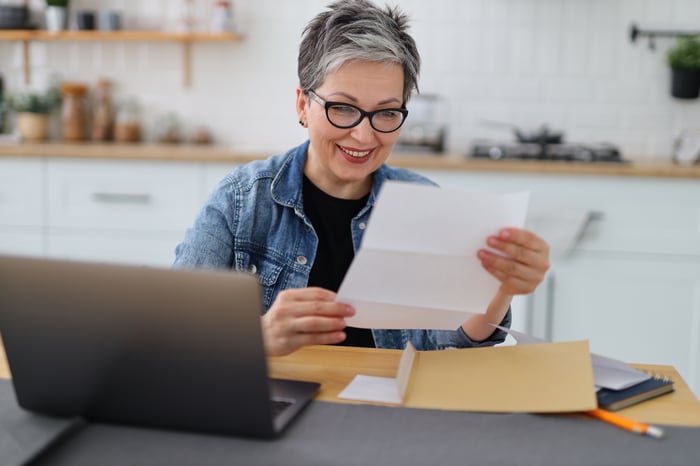 A retired woman reviewing a paper document while seated.