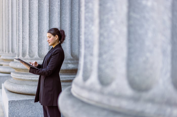 A lawyer uses a tablet computer outside of a courthouse.