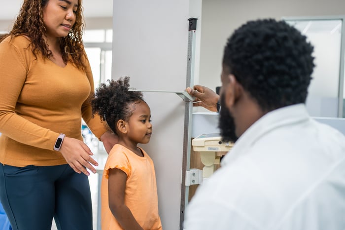 A person measuring a child's height in an office.