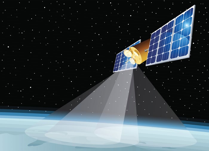 Satellite with large solar panels beaming transmissions to Earth.