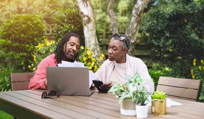 Two people at outside table looking at laptop.