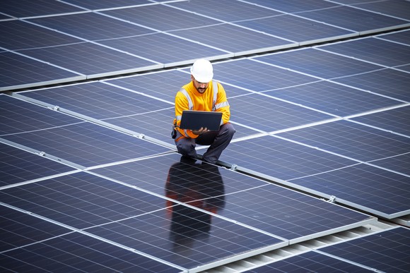 technician amid large solar panel farm.