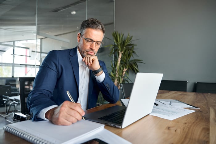 A professionally dressed person at a table taking notes.