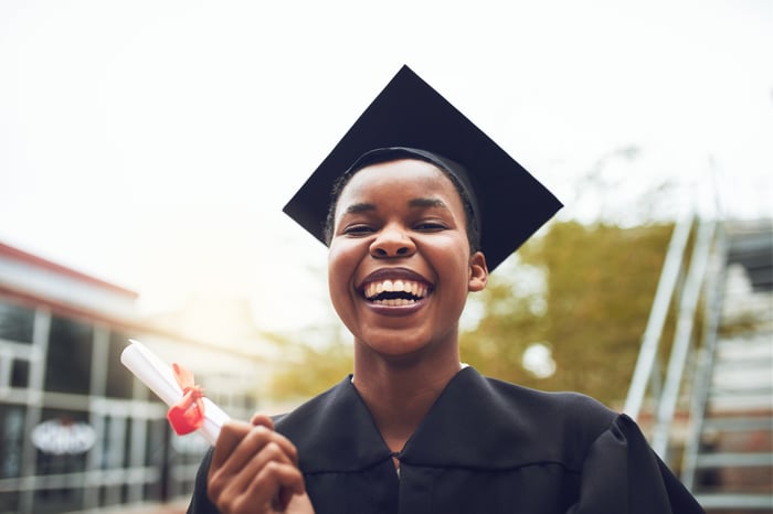 Smiling graduate holding diploma.