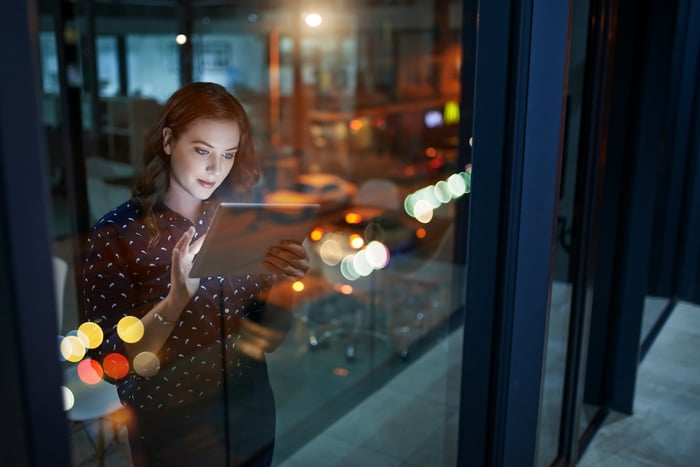 A person works on a tablet by the window in an office building.