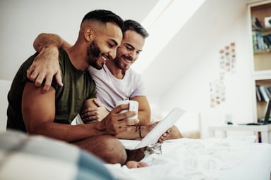 21_07_21 A couple sitting in bed looking at a computer _GettyImages-1174486567
