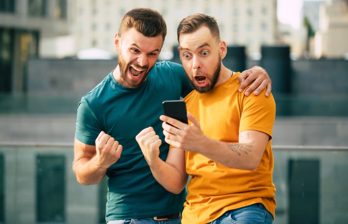 Two people looking at a phone and acting excitedly.