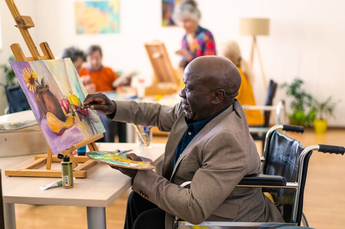 A person paints on a canvas in an art class.