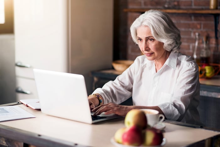 A person at a laptop in a kitchen setting.