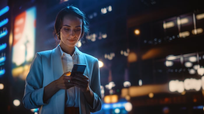 A person uses a smartphone on a city street.