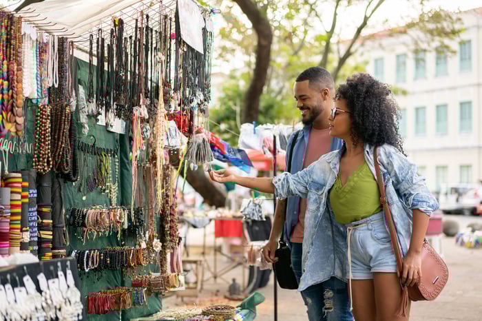 Two people shop in an outdoor market.