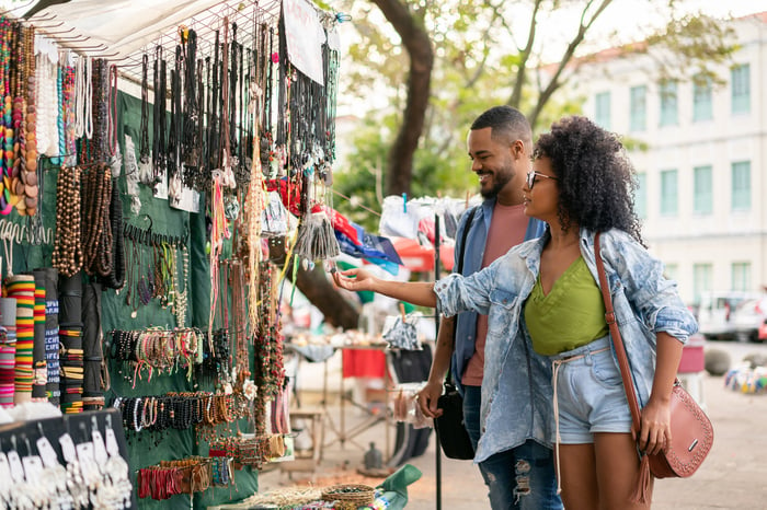 Two people shop in an outdoor market.