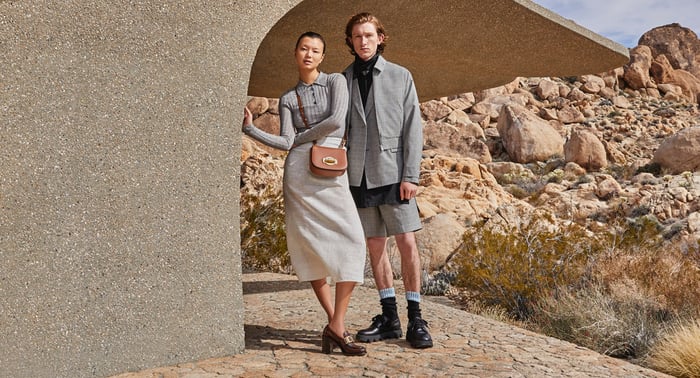 A couple standing together in a desert scene in a Farfetch ad.