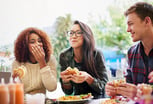 three friends eating burgers outdoors