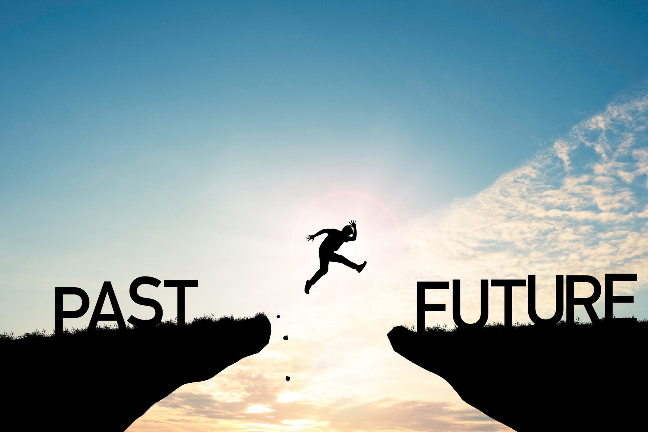 22_03_21 A person jumping between cliffs one with past written on it and the other with future _GettyImages-1295289697