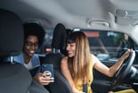 Two people looking at a phone in a car