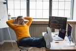 Investor with smile on face and feet on desk -- GettyImages-1323758599