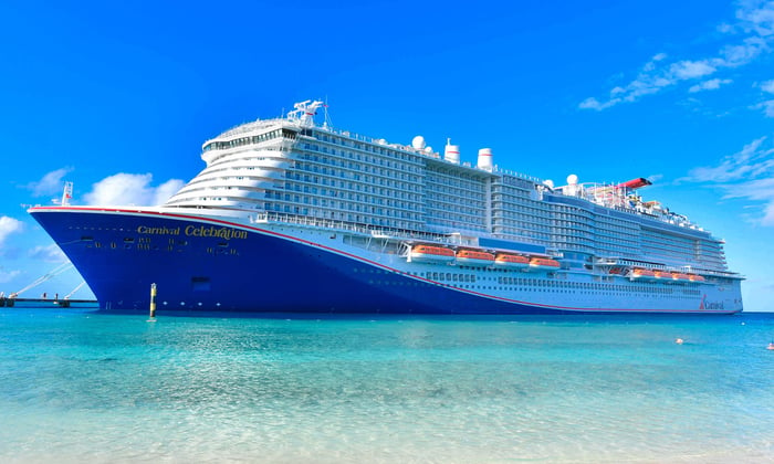 A Carnival cruise ship is shown, anchored near a dock.