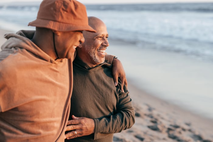 Two men embracing while watching the surf.