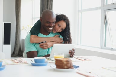 A couple looking at a tablet during breakfast.