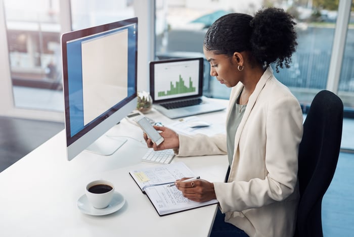 An investor analyzes a stock in front of two computers in an office.