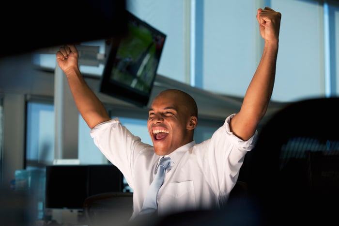 Person looking at computer monitor cheering because the stock market went up.