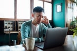 person with a worried expression looking at a laptop