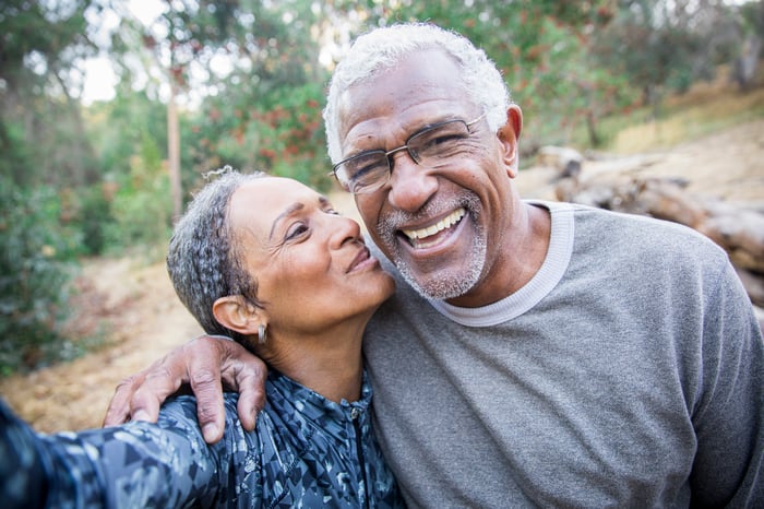 A couple is outdoors, smiling.