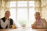 senior man and woman sitting at table resting their faces on their hands looking bored couple retirement