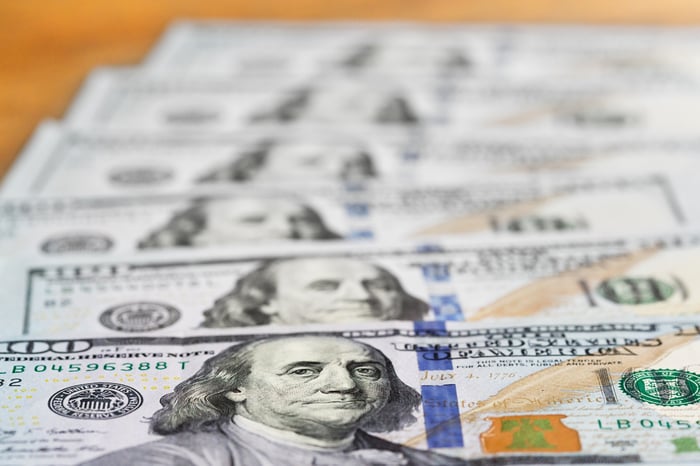 Six one-hundred-dollar bills staggered atop one another.