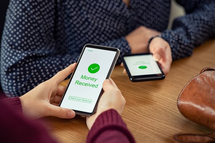 Two people using their smartphones to complete a digital payment. 