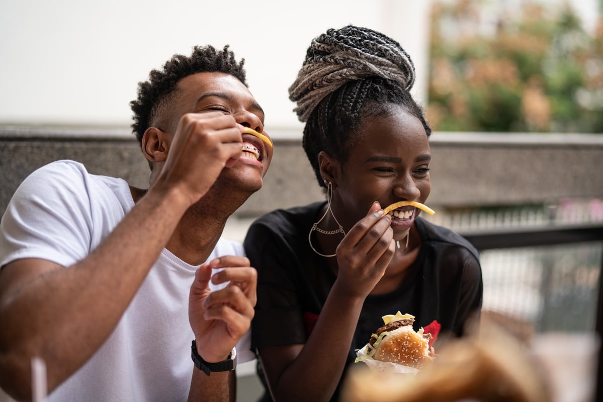 24_01_22 Two people eating burgers and fries outside _MF Dload GettyImages-972911836-1200x800-5b2df79