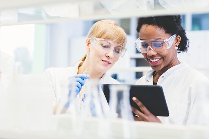 Two scientists smile while working in a lab.