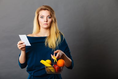 young person holding produce and receipt upset about cost price sticker shock inflation