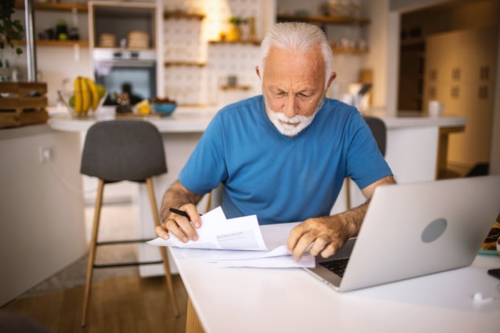 A person at a laptop with papers in front of them.