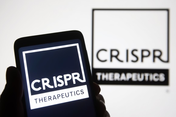 The shadow of a hand holds a phone with the CRISPR Therapeutics logo on it.