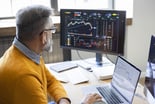 analyst_analyzing_stock_charts_on_desktop_and_laptop